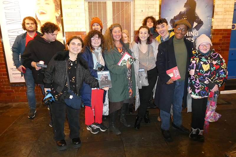 Group posing for photo on street outside theater